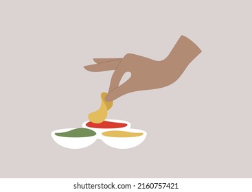 A hand dipping a potato chip into a tomato sauce