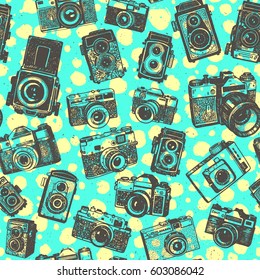 Hand drawing retro photo cameras on green font with yellow blobs of seamless pattern background.