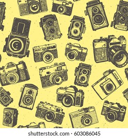 Hand drawing retro photo cameras on yellow base of seamless pattern background.