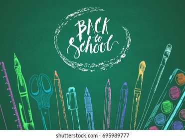 Hand drawn back to school background with colorful sketch of pen, pencil, ruler, paints, brush and lettering. Design template on green chalkboard.