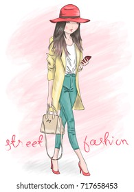 Hand drawn beautiful cute girl with smart phone on background with an inscription street fashion. Vector illustration.