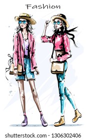 Hand drawn beautiful young girls in hats. Two stylish women. Fashion woman look. Sketch.