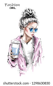 Hand drawn beautiful young woman holding plastic coffee cup. Stylish blonde hair girl. Fashion woman look. Sketch.