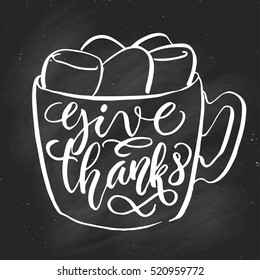 Hand drawn cup with marshmallow doodle with give thanks fancy lettering, on black chalkboard background. Vector illustration.