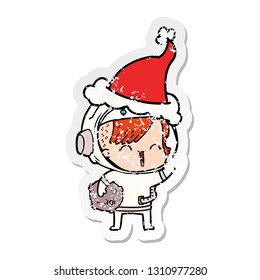 hand drawn distressed sticker cartoon of a happy spacegirl holding moon rock wearing santa hat