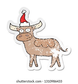 hand drawn distressed sticker cartoon of a bull wearing santa hat