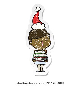 hand drawn distressed sticker cartoon of a happy boy with stack of books wearing santa hat