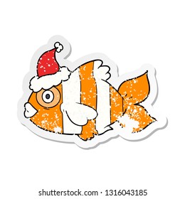 hand drawn distressed sticker cartoon of a exotic fish wearing santa hat