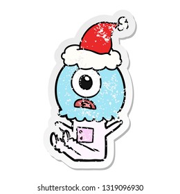 hand drawn distressed sticker cartoon of a cyclops alien spaceman wearing santa hat