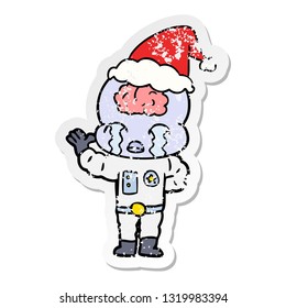 hand drawn distressed sticker cartoon of a big brain alien crying wearing santa hat