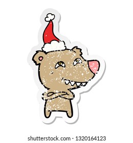 hand drawn distressed sticker cartoon of a bear showing teeth wearing santa hat