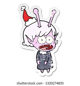 hand drawn distressed sticker cartoon of a shocked alien girl wearing santa hat