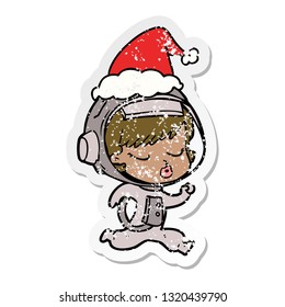 hand drawn distressed sticker cartoon of a pretty astronaut girl running wearing santa hat