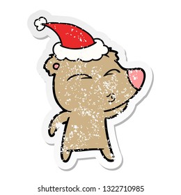 hand drawn distressed sticker cartoon of a whistling bear wearing santa hat