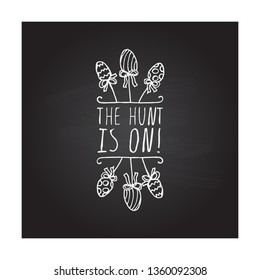 Hand drawn easter typographic element on chalkboard background. The hunt is on. Suitable for print and web