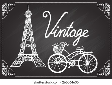 Hand drawn Eiffel tower and vintage bicycle on chalkboard with ornamental swirl.