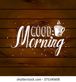Hand drawn Good morning inscription and cup of coffee on wooden background. Vector illustration for graphic design.