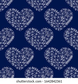 Hand drawn heart shape is filled with doodles of flowers, stylized plants, dots. Seamless pattern on blue background for fabric and other.