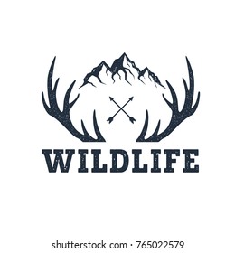 Hand drawn inspirational label with mountains and antlers textured vector illustrations and "Wildlife" lettering.