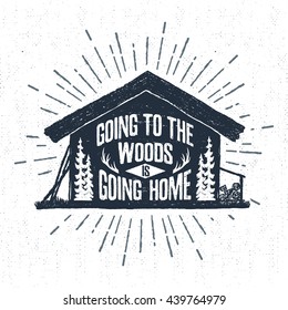 Hand drawn label with textured wooden cabin vector illustration and "Going to the woods is going home" lettering.