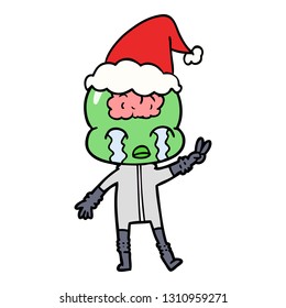 hand drawn line drawing of a big brain alien crying and giving peace sign wearing santa hat
