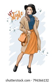 Hand drawn sketch of a stylish young woman in coat. Fashion woman with a bag in a coat and hat. Casual style. Fashion model posing. Vector illustration.