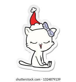hand drawn sticker cartoon of a cat with bow on head wearing santa hat