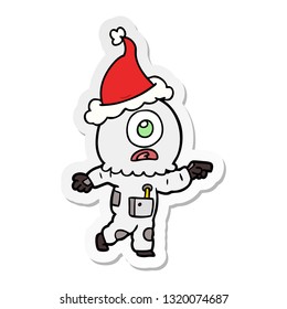 hand drawn sticker cartoon of a cyclops alien spaceman pointing wearing santa hat