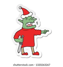 hand drawn sticker cartoon of a goblin with knife wearing santa hat