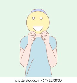 Hand drawn style vector illustration of a man holding an smiling emoji sign in front of his face. Concept of good emotion, cheerful mood, positive facial expression.