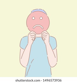 Hand drawn style vector illustration of a man holding an sad emoji sign in front of his face. Concept of bad emotion, pessimistic mood, negative facial expression.