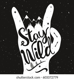 Hand drawn style vector inspirational and motivational typography poster with lettering quote - Stay Wild. Adventure, travel illustration with hand, arrows, pine trees, stars and mountains