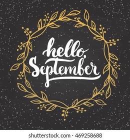 Hand drawn typography lettering phrase Hello, September with golden wreath on the chalkboard background. Fun brush inscription for photo overlays, greeting and invitation card or t-shirt print design