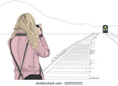 Hand drawn vector illustration. Young woman stands on train tracks for a photo of an approaching train. Concept of outdoor adventure and photography journey. Black and white background.