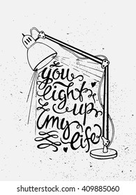 Hand drawn vintage illustration with hand lettering and a lamp isolated on white. You light up my life. Quote. This illustration can be used as a print on t-shirts and bags or as a poster. 