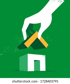 A hand finishing the house by adding the roof