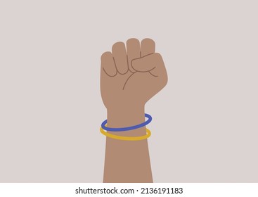 A hand folded into a fist, blue and yellow wristbands, fight for freedom and peace, support Ukraine