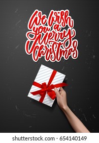 Hand with a gift box  Hand drawn calligraphy. concept handwritten Christmas in the air 