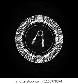hand gripper icon inside chalkboard emblem on black board