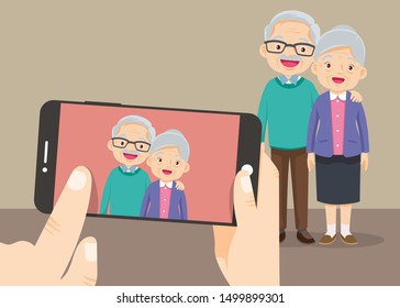 hand hold smartphone with the grandparents take photo.Old people selfie. Senior people smiley face smartphone photo.Elderly couple making selfie.Modern senior couple.