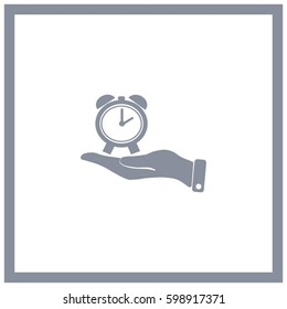 hand holding a alarm clock. The clock shows the time