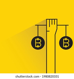 hand holding balance of bitcoin with shadow on yellow background