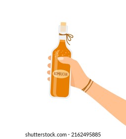 Hand, die eine Flasche mit Kombucha-Tee auf weißem Hintergrund hält