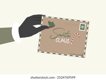 Hand Holding Christmas Envelope. hand holds a brown envelope addressed to Santa Claus, decorated with Christmas symbols. The envelope is made from recycled paper. Sustainable christmas concept