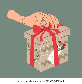 Hand holding Christmas gift in kraft paper with tag and berries. Present box in craft wrapping paper with bow and branches. Colored flat vector illustration isolated on beige background.