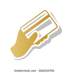 Hand holding a credit card. Vector. Golden gradient icon with white contour and rotated gray shadow at white background.