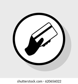Hand holding a credit card. Vector. Flat black icon in white circle with shadow at gray background.