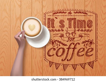 hand holding cup of latte on wooden  background.   it`s time for coffee 