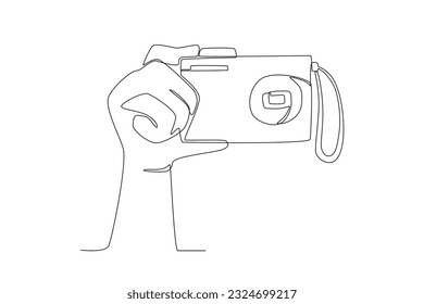 A hand holding a digital camera. World photography day one-line drawing