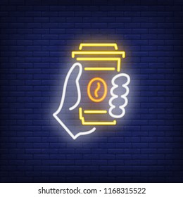 Hand holding disposable coffee cup neon sign. Cafe, break, beverage concept. Advertisement design. Night bright neon sign, colorful billboard, light banner. Vector illustration in neon style.